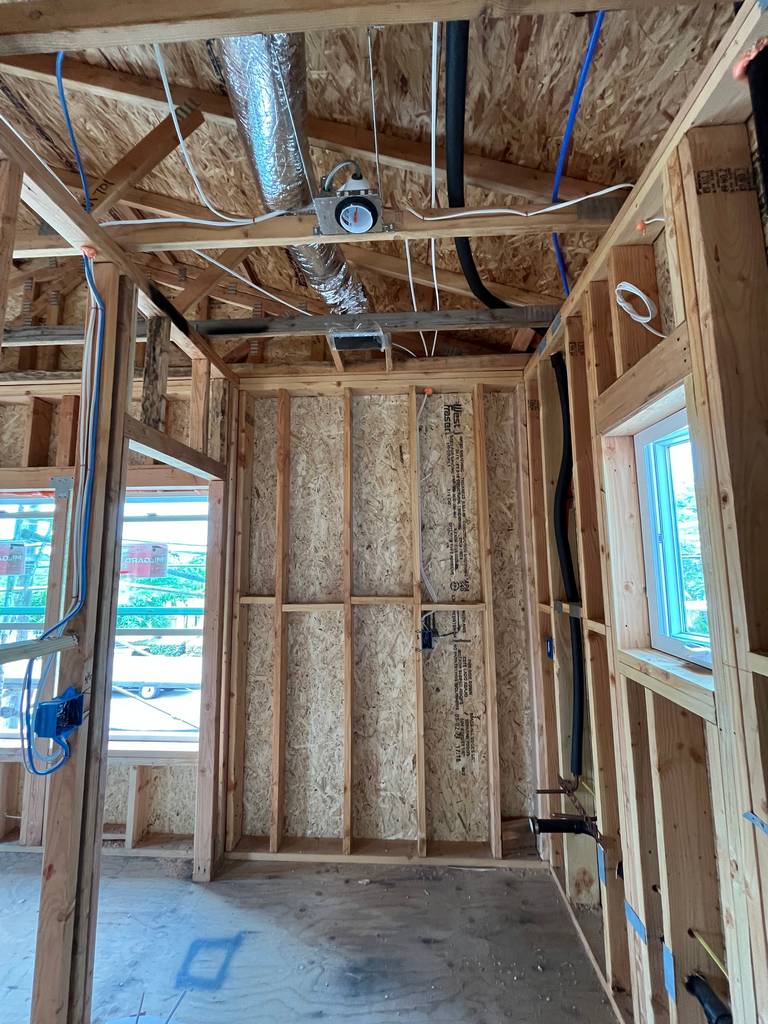 Bathroom framing with ceiling ductwork, plumbing, and electrical rough-ins visible.