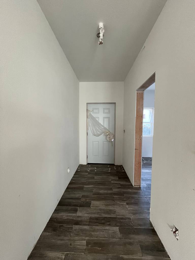 Hallway interior showing drywall taping and mudding in early construction stage before finishing work.