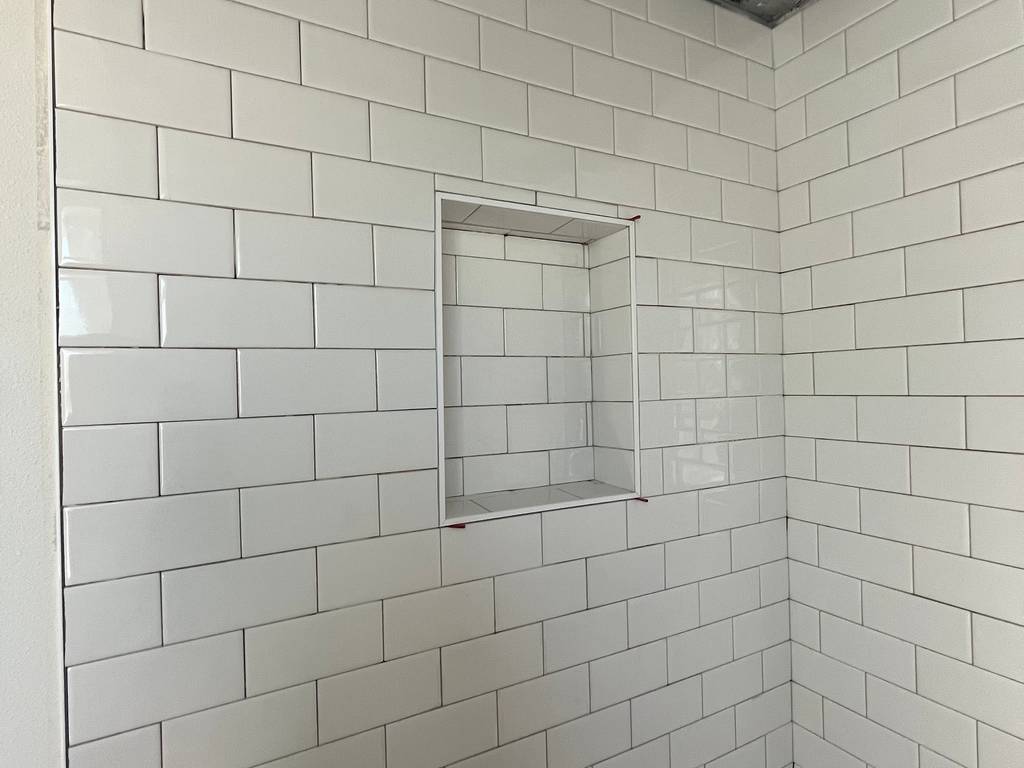 tiled shower featuring precision-set white subway tile on walls and ceiling.