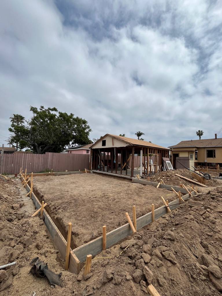 Freshly excavated foundation pit with full perimeter formwork staged for concrete pour and string lines in place for layout.