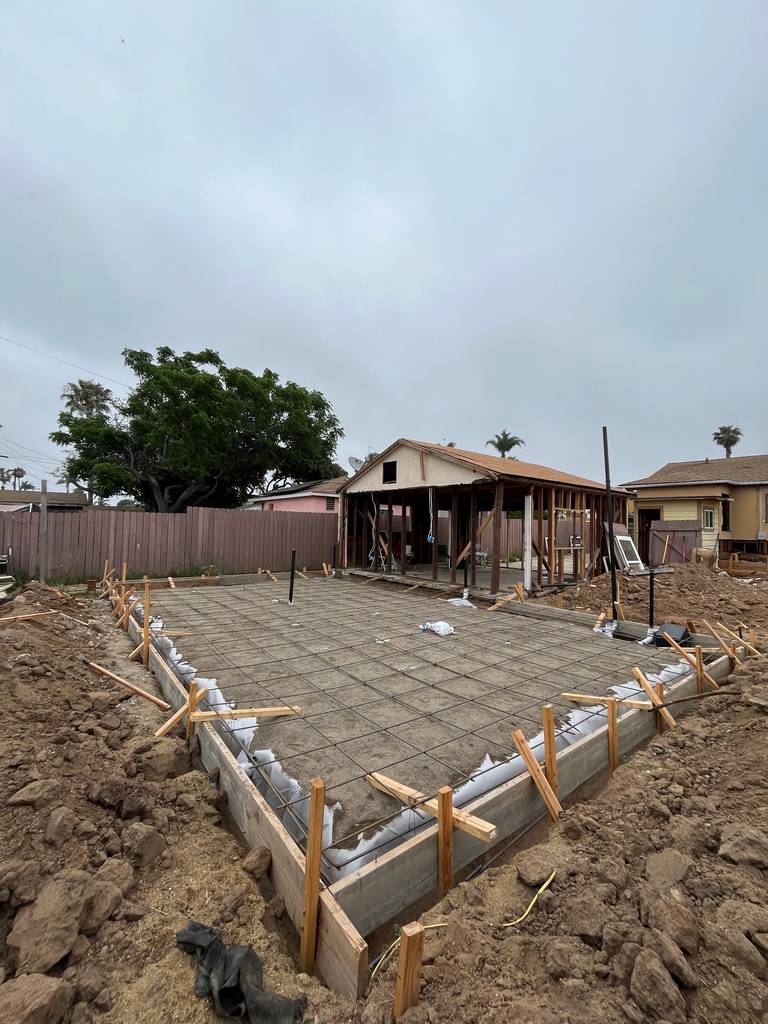 Full foundation prep completed with installed rebar and formwork. Plumbing risers positioned at strategic locations for vertical connections.
