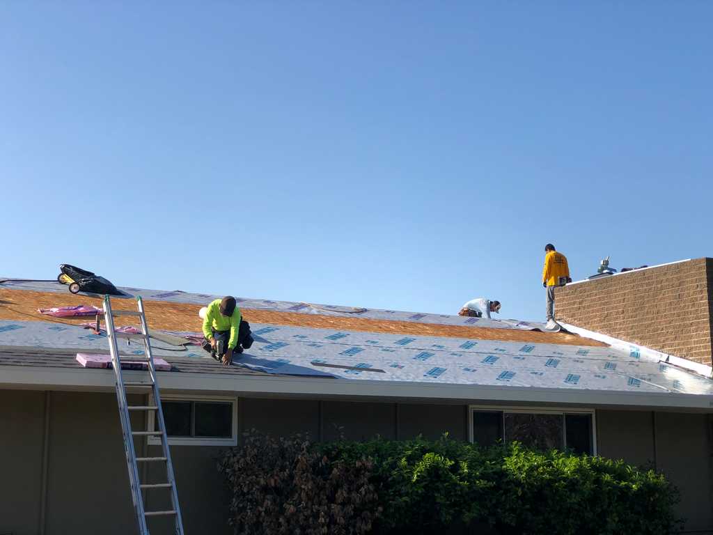 a2mContractors laying down roof protection over the roof sheathing